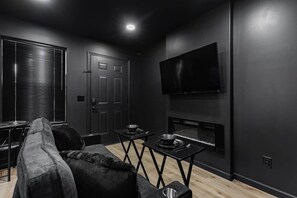A modern living room with a sofa, a TV mounted on the wall, and a small table with a bowl and spoon. - *NEW* Downtown* Hot Tub* Ping Pong (Bristol)