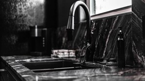 Une cuisine moderne dotée d’un robinet élégant, d’un évier et d’un plan de travail en marbre.