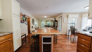 Una cocina amplia con una larga mesa de madera, armarios de madera y un enfriador de vino empotrado.