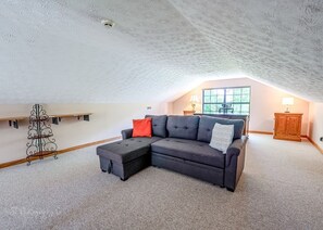 Ein Loft-Zimmer mit Ecksofa, kleinem Hocker, einem Metallregal und einem Holzkasten.