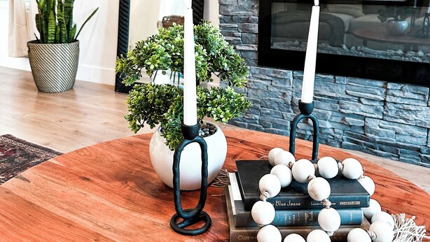 Un salon chaleureux avec une cheminée en pierre, un grand miroir et une table basse en bois sur laquelle sont posés des livres et des objets décoratifs.