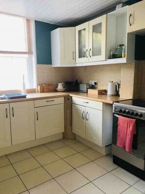 Kitchen features a sink, stove, and countertop with a kettle and toaster.