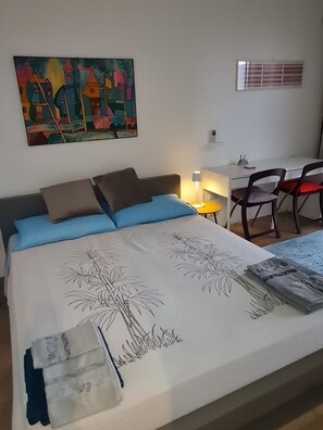 Ett sovrum med en säng, kuddar, ett skrivbord och en stol.