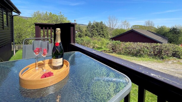 Een glazen tafel met een fles Moët & Chandon champagne, twee glazen en frambozen op een houten dienblad.