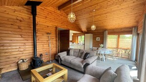 Indbydende interiør i en træhytte med sofa, sofabord og spiseplads.