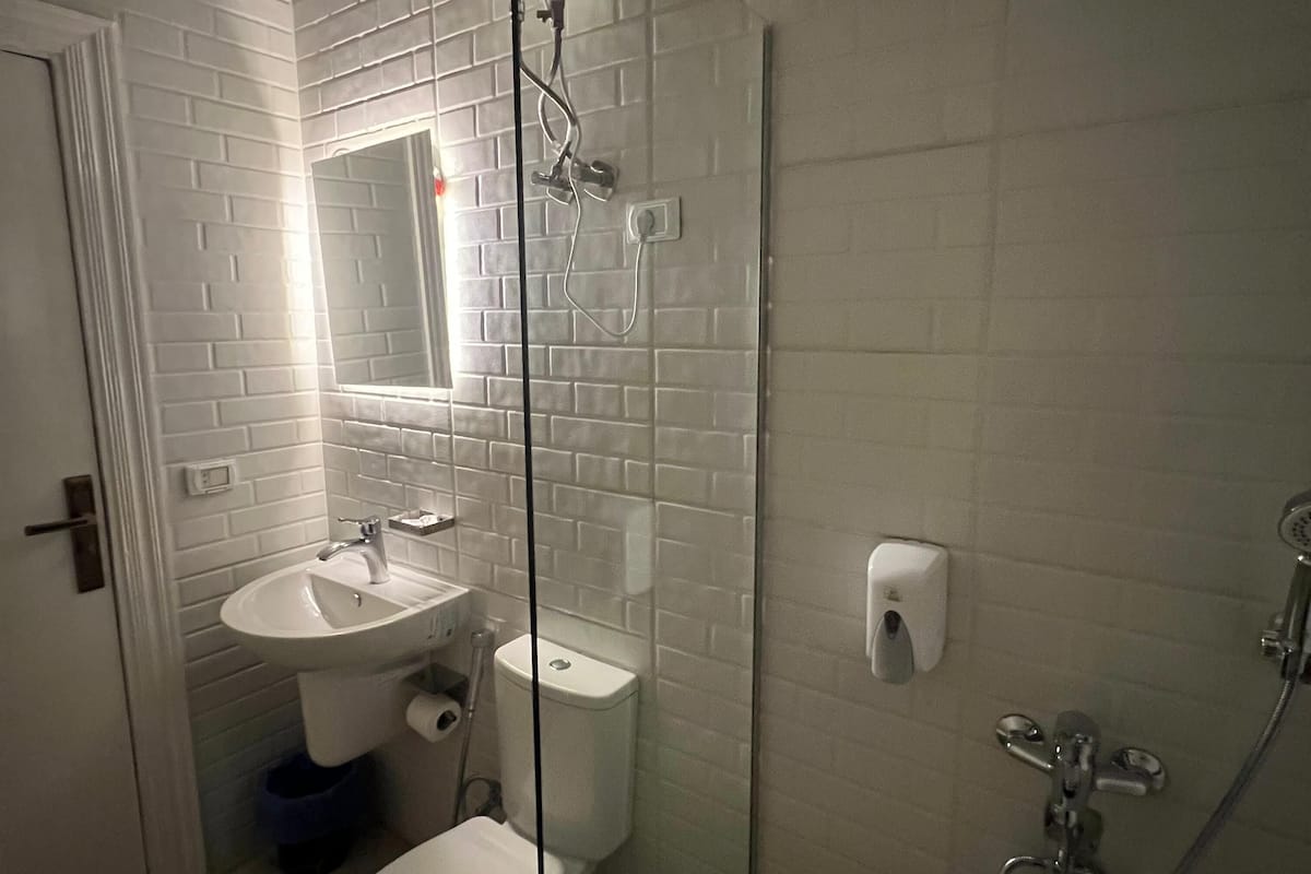 Kylpyhuone, jossa on valkoinen pesuallas, wc ja suihkutila.