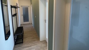 A hallway with wooden flooring, white walls, and doors leading to other rooms. - Modern vacation apartment "Stilapartment Oasis 1" close to the center (Wernigerode)