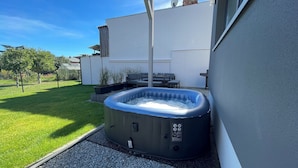 A hot tub in a backyard with a patio, a white wall, and a clear sky. - Modern vacation apartment "Stilapartment Oasis 1" close to the center (Wernigerode)