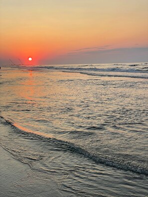 Una playa con olas y un atardecer.