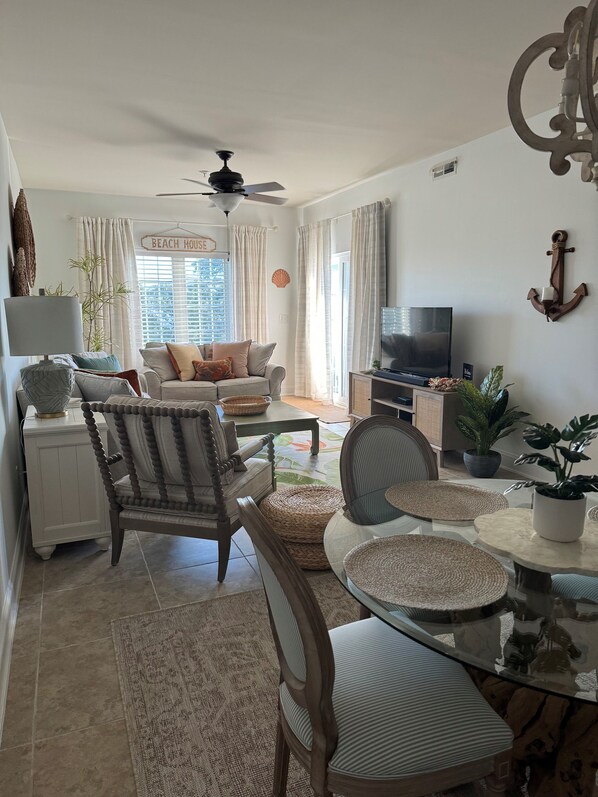 Una sala de estar con sofá, sillón, televisión y objetos decorativos.