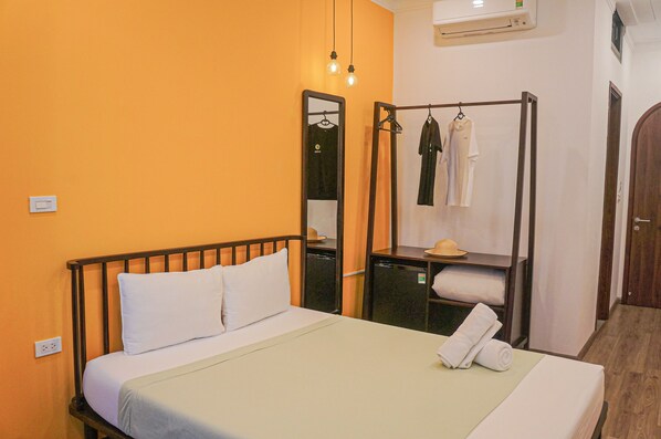Une chambre d’hôtel avec un lit, un miroir, une armoire et une petite table sur laquelle se trouvent un chapeau et des serviettes.