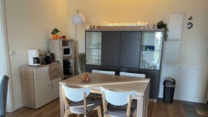 A modern kitchen with a dining table, chairs, and a coffee machine. - Apartment "Moin im Deichgraf" on the Wremer beach and cutter harbor (Wurster Nordseeküste)