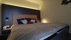 A modern bedroom with a bed, bedside tables, and a wall-mounted light fixture. - Apartment "Moin im Deichgraf" on the Wremer beach and cutter harbor (Wurster Nordseeküste)