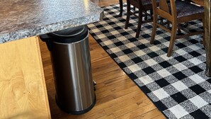 A kitchen with wooden cabinets, a granite countertop, a stainless steel trash can, and a checkered rug. - Cozy and quaint farmhouse on an acreage  (Mountain Lake)