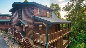 Une cabane en rondins avec une véranda et un escalier menant à une terrasse.