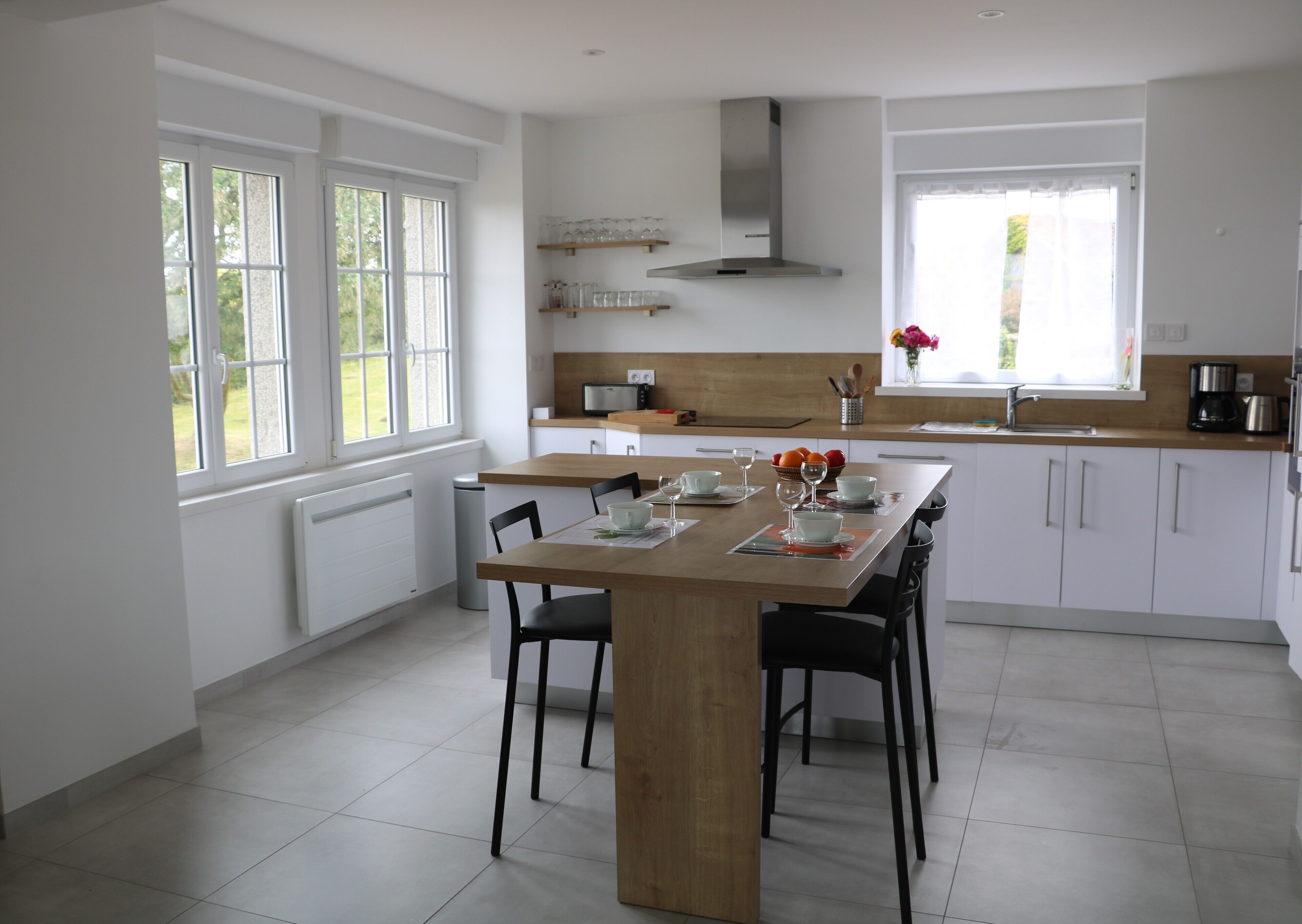 Eine moderne Küche mit Holztisch, weißen Schränken und einem großen Fenster.