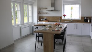Una cocina moderna con una mesa de comedor de madera, armarios blancos y un ventanal grande.