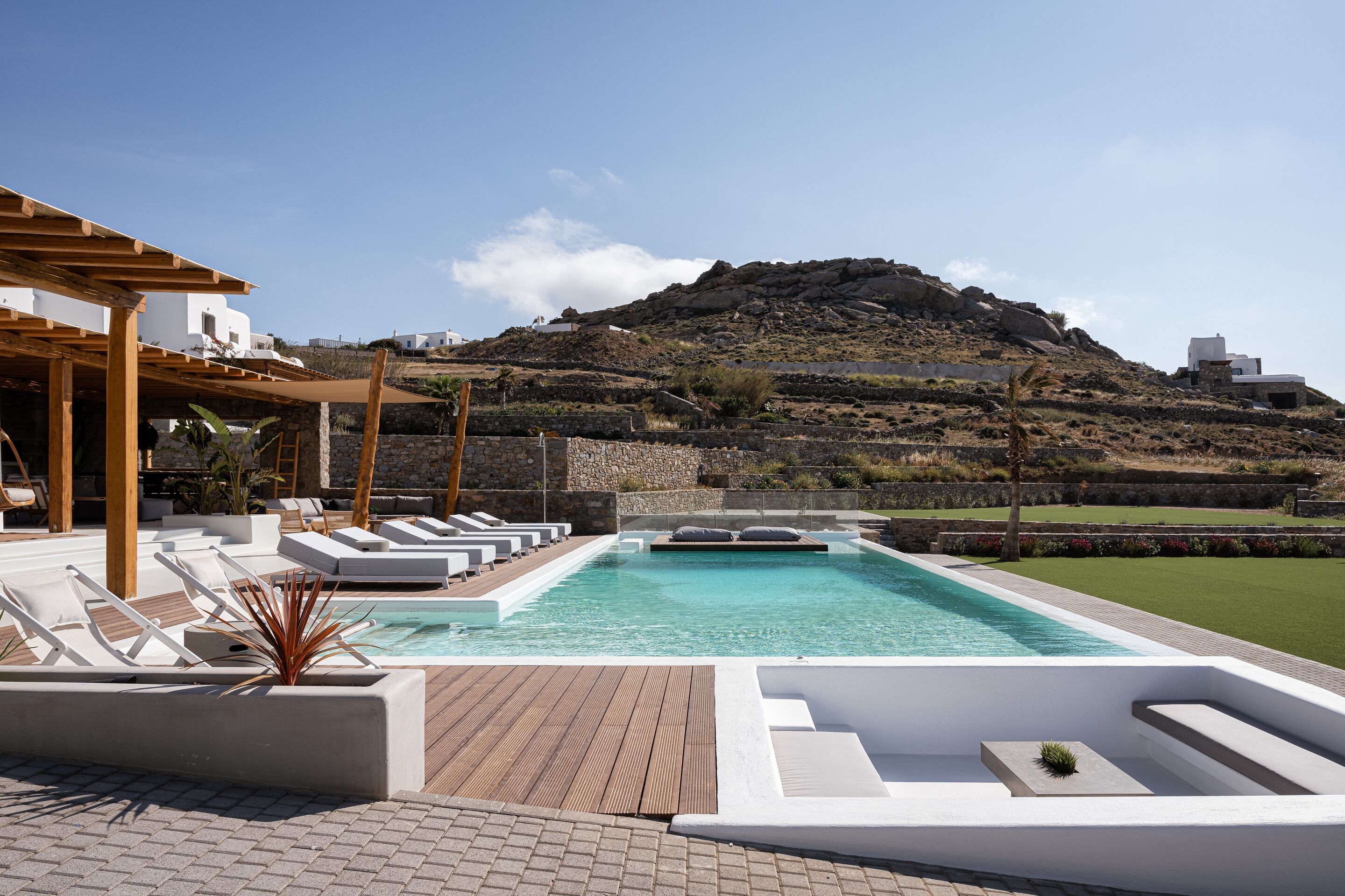 A pool area with lounge chairs and a view of a mountain.