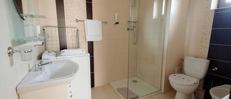A modern bathroom with a glass-enclosed shower, a white sink, and a toilet.
