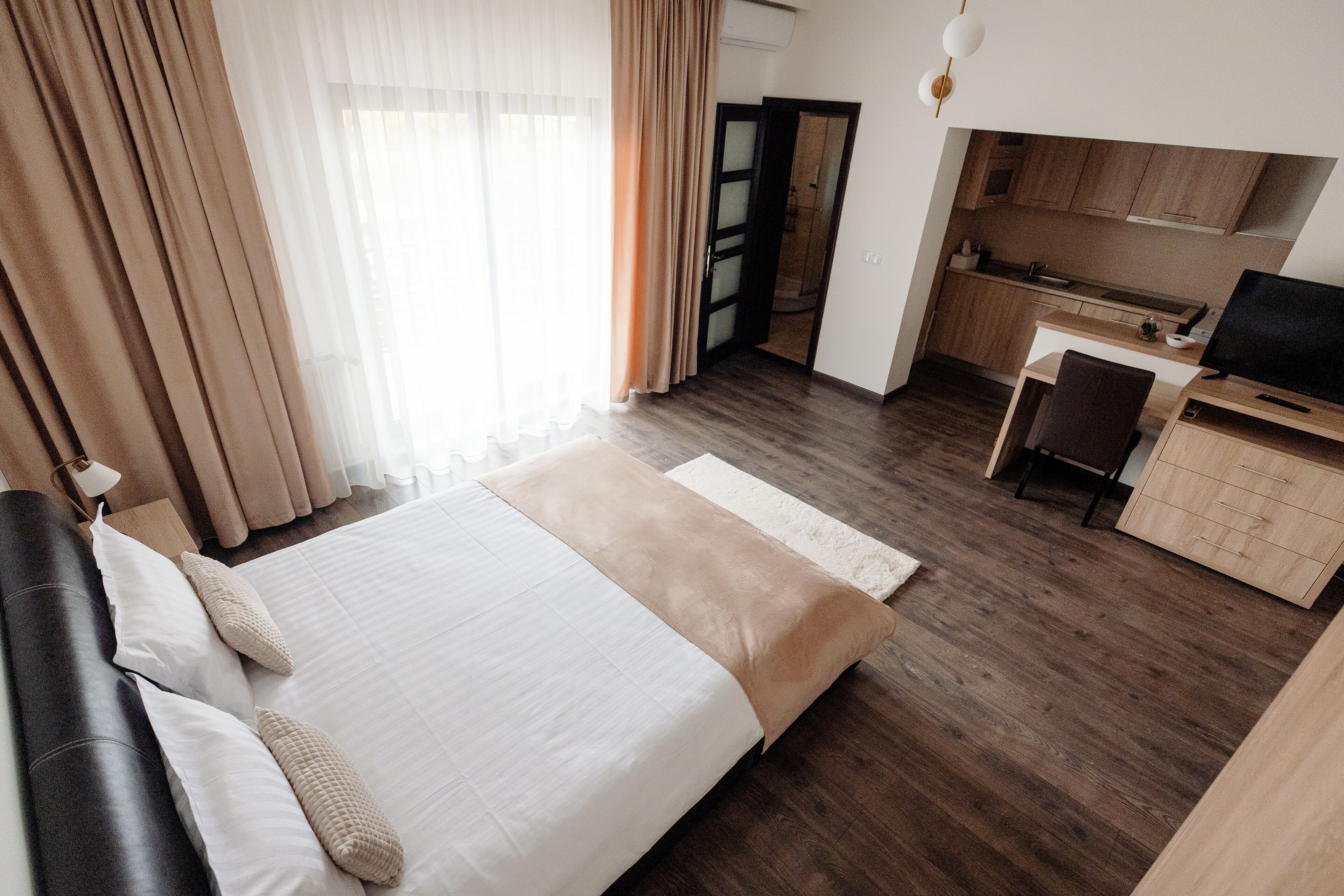 A hotel room with a bed, a desk, a chair, and a television.