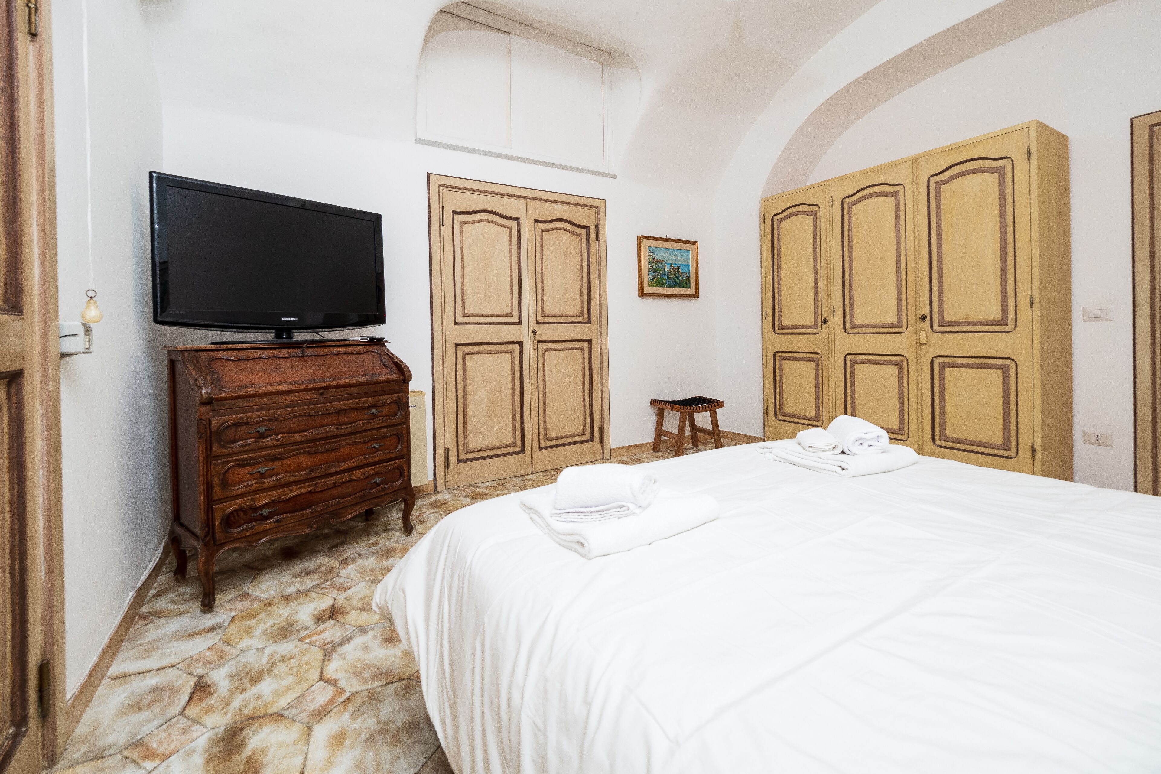 Un dormitorio con cama, cómoda, televisor y armarios de madera.