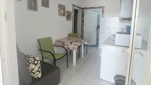 A compact living space with a dining area, kitchenette, and a sofa with a patterned cushion.