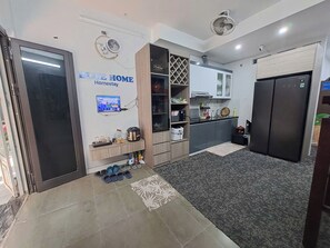 Une cuisine moderne équipée d’un four encastré, d’un réfrigérateur et d’un four à micro-ondes. On y trouve également un petit coin salon avec un tapis et une table basse.