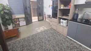 A compact kitchen with grey cabinets, a countertop, and a small dining area. - Blue Homestay Cau Giay (Hanoi)