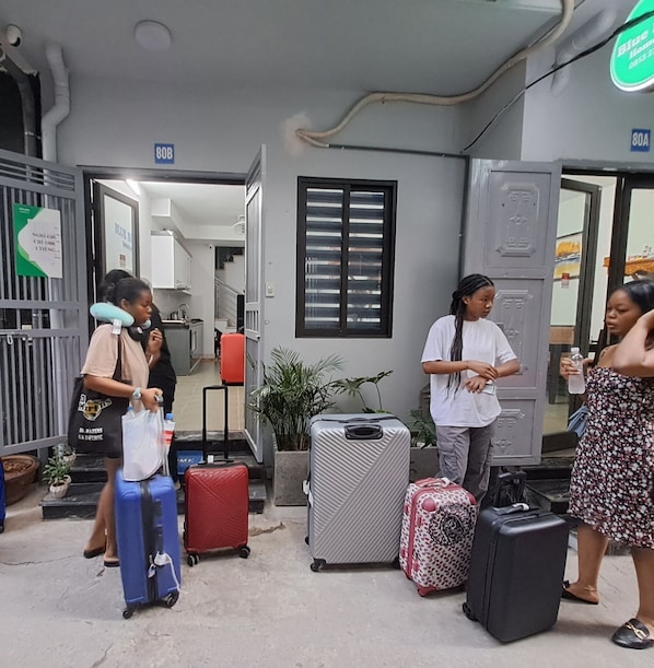 A building entrance with multiple suitcases and a person carrying a bag. - Blue Homestay Cau Giay (Hanoi)