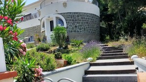A set of stone steps leading to a white building with a curved roof and a stone facade. - Logement de 50 m2 en rez de Jardin (Fréjus)