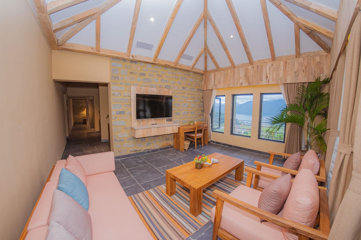 A spacious living area with a stone wall, a flat-screen TV, a wooden coffee table, and a sofa.