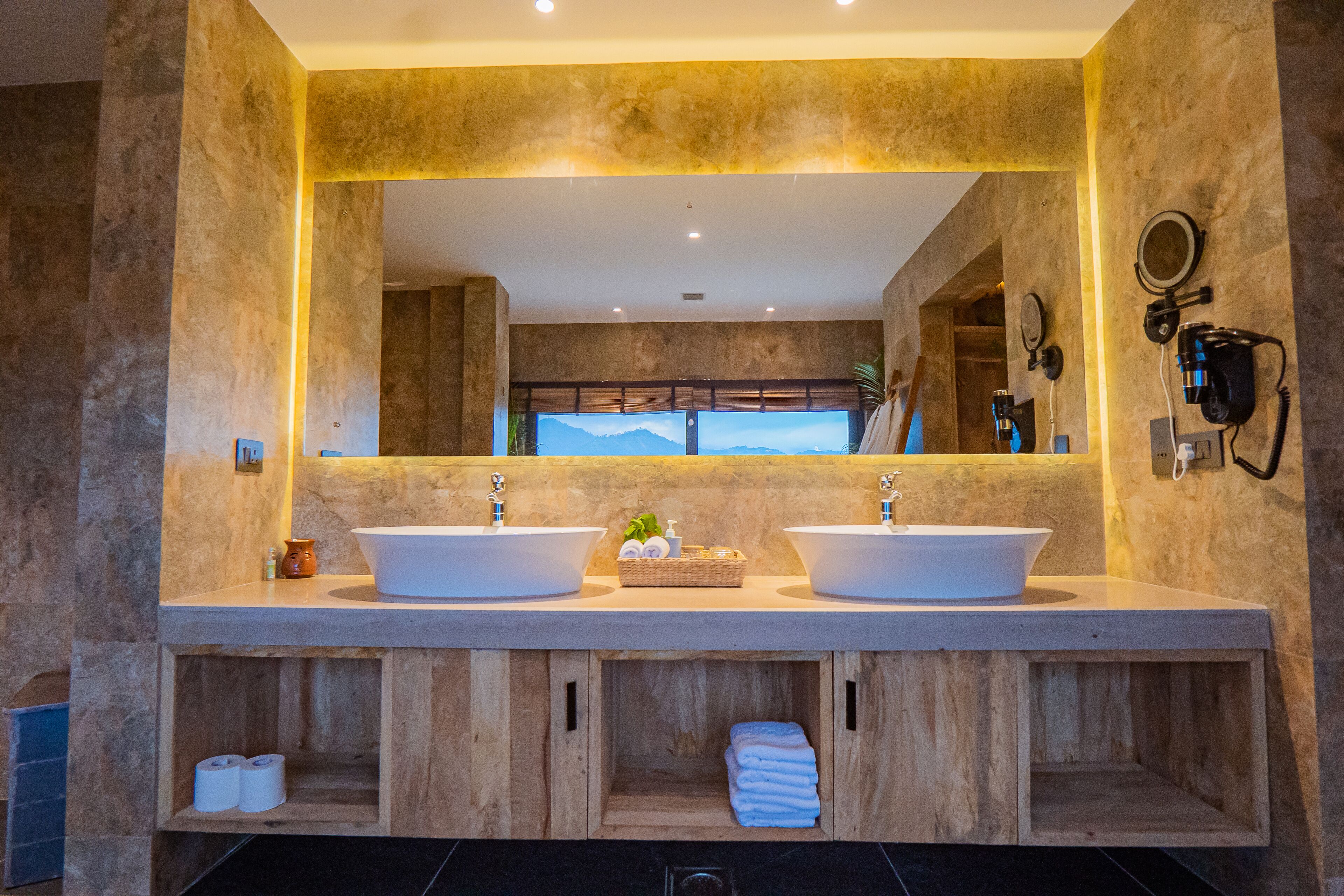 Un baño con dos lavamanos, armarios de madera y un espejo grande.
