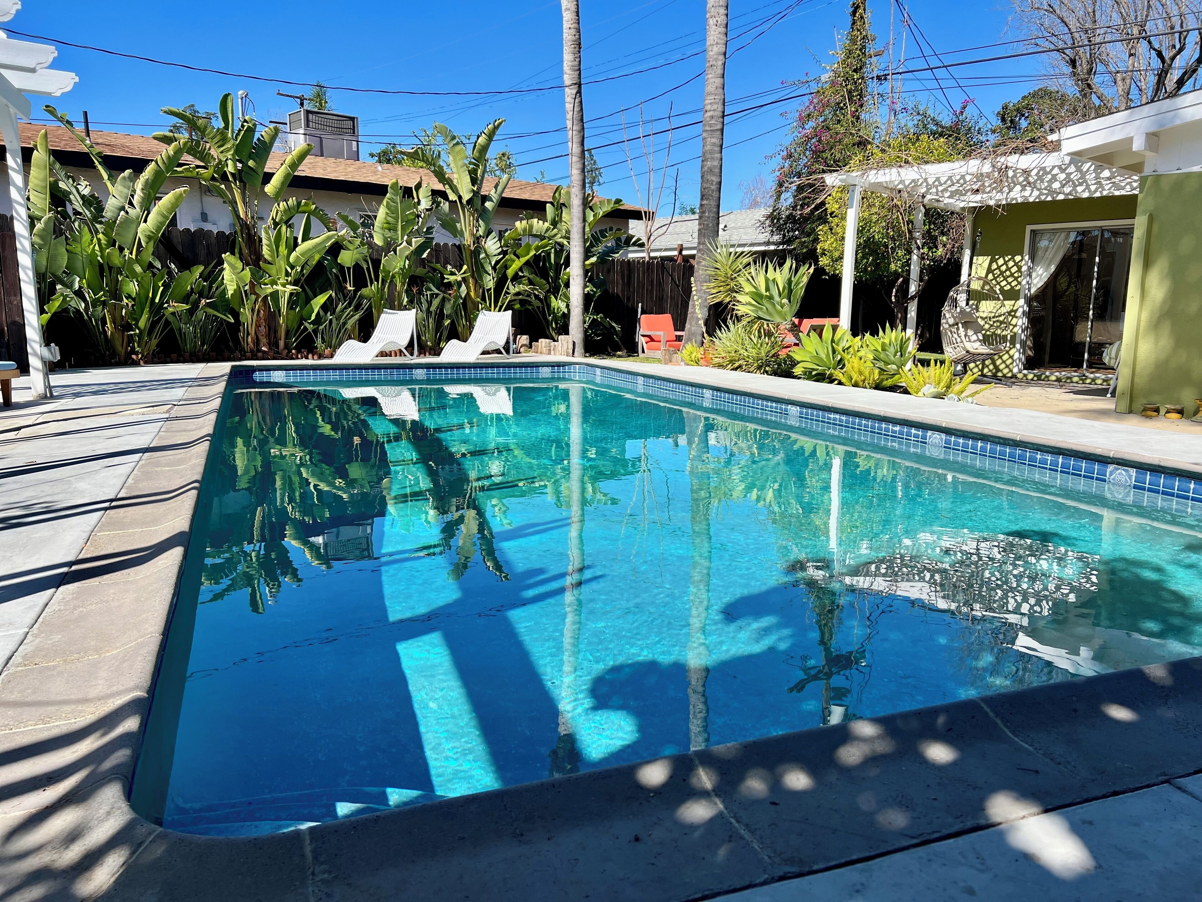 A rectangular swimming pool with clear blue water, surrounded by a tiled deck.