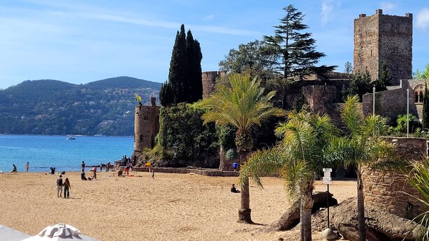 A beach with a historic stone tower and lush greenery.