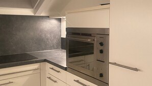 A kitchen with white cabinets, a black countertop, and a Siemens oven.