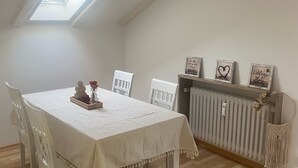 A dining area with a table set for four, white chairs, a radiator, and a skylight above.