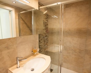 A modern bathroom with a glass-enclosed shower, a beige sink, and a mirror. - Haus Cristal  (Leukerbad)
