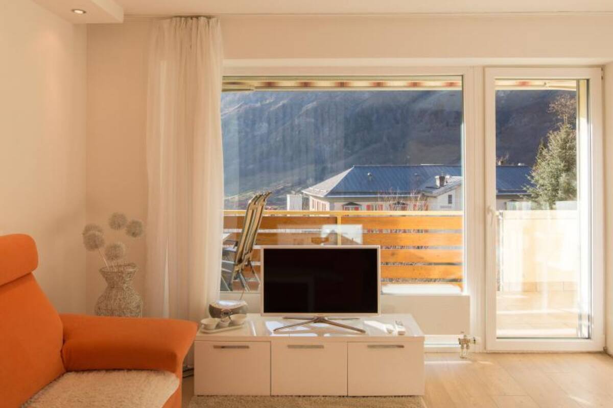 A modern living room with a large window, a flat-screen TV, and a sofa.