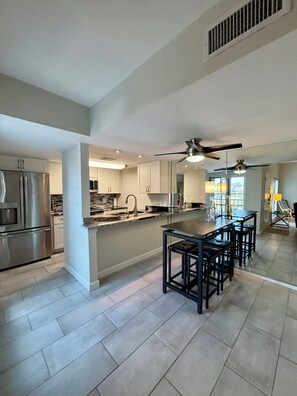 A modern kitchen with a central island, stainless steel appliances, and a ceiling fan.