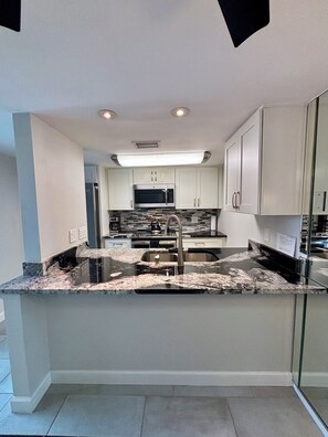 A modern kitchen with a central island, stainless steel appliances, and a tiled backsplash.