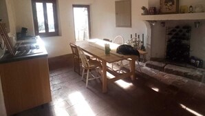 Un comedor con mesa y sillas de madera, chimenea y zona de cocina con estufa.