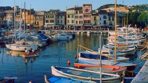 Un port de plaisance où sont amarrés différents types de bateaux, entouré de bâtiments abritant des boutiques et des restaurants.