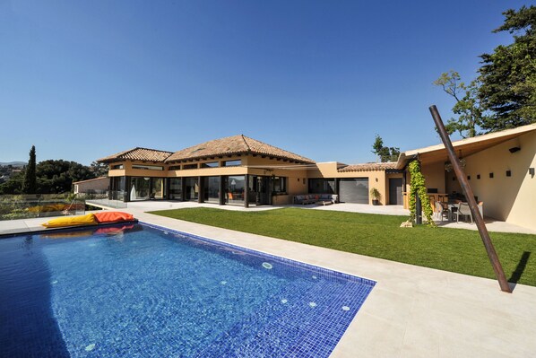 A modern house with a swimming pool, a patio, and a well-maintained lawn.