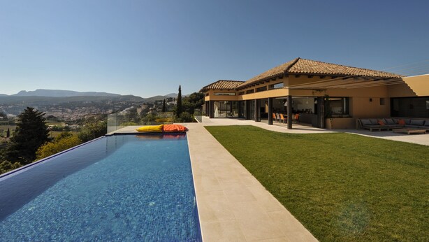 Une maison moderne dotée d’une piscine, d’un patio et offrant une vue sur la ville et les montagnes.