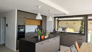 Une cuisine moderne dotée d’un îlot central, de meubles de couleur grise et d’un éclairage suspendu.