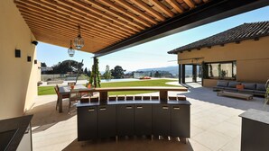 Une terrasse extérieure dotée d’une pergola en bois, d’un coin repas et d’un espace détente avec un canapé et une table basse.
