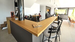 Une cuisine moderne avec un îlot central en bois, des tabourets de bar et des luminaires suspendus.