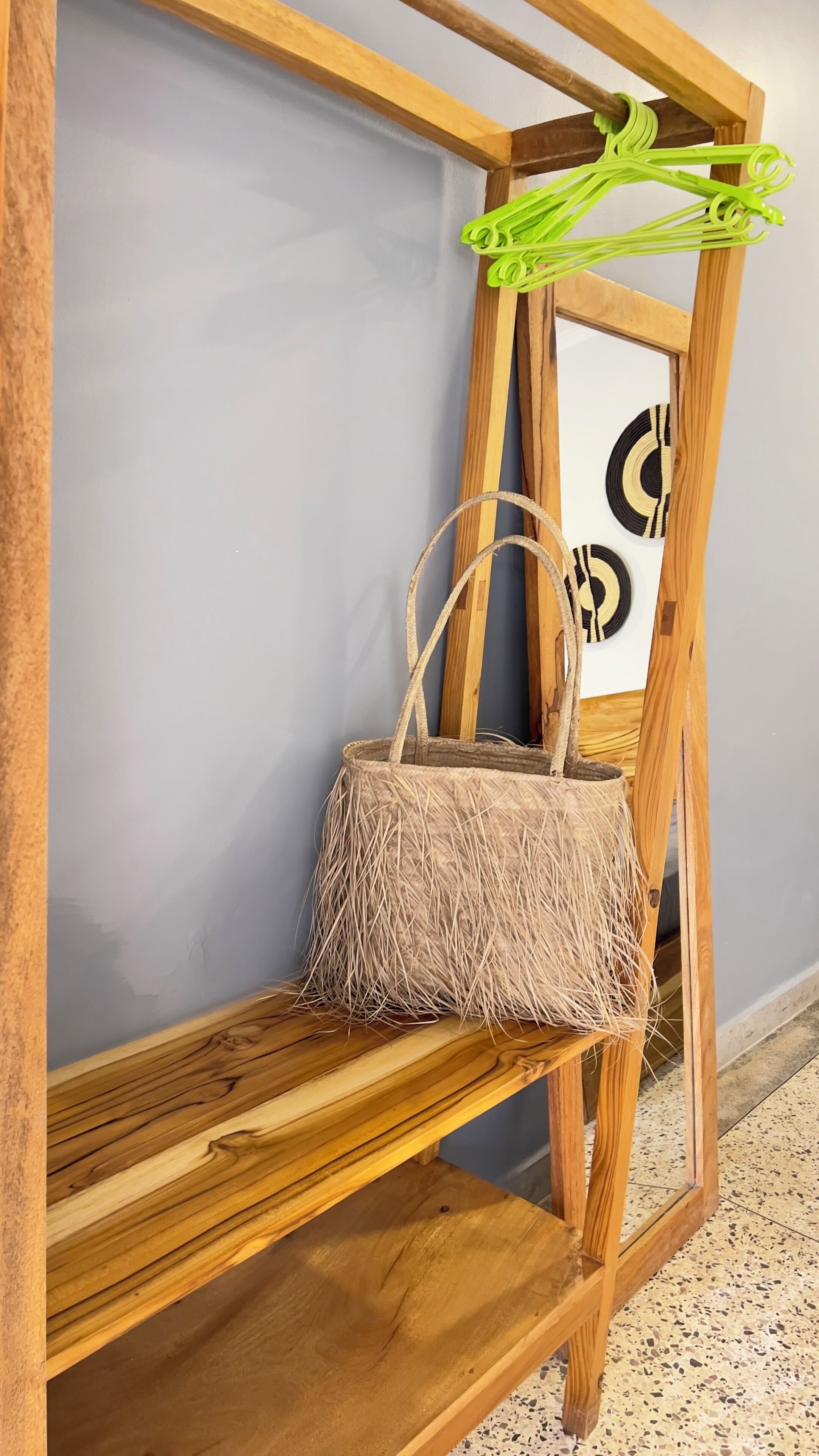 Una estantería de madera con una cesta tejida y un cuadro enmarco.