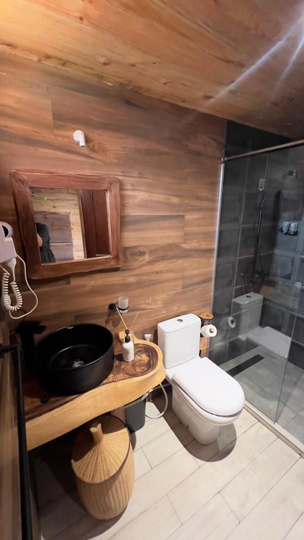 Un baño moderno con tocador de madera, inodoro y cabina de ducha de vidrio.