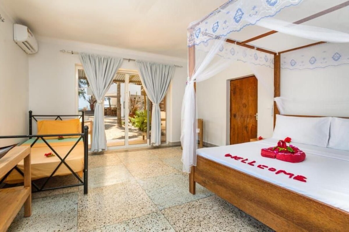 Un dormitorio con una cama, un banco, una puerta y vistas al exterior.
